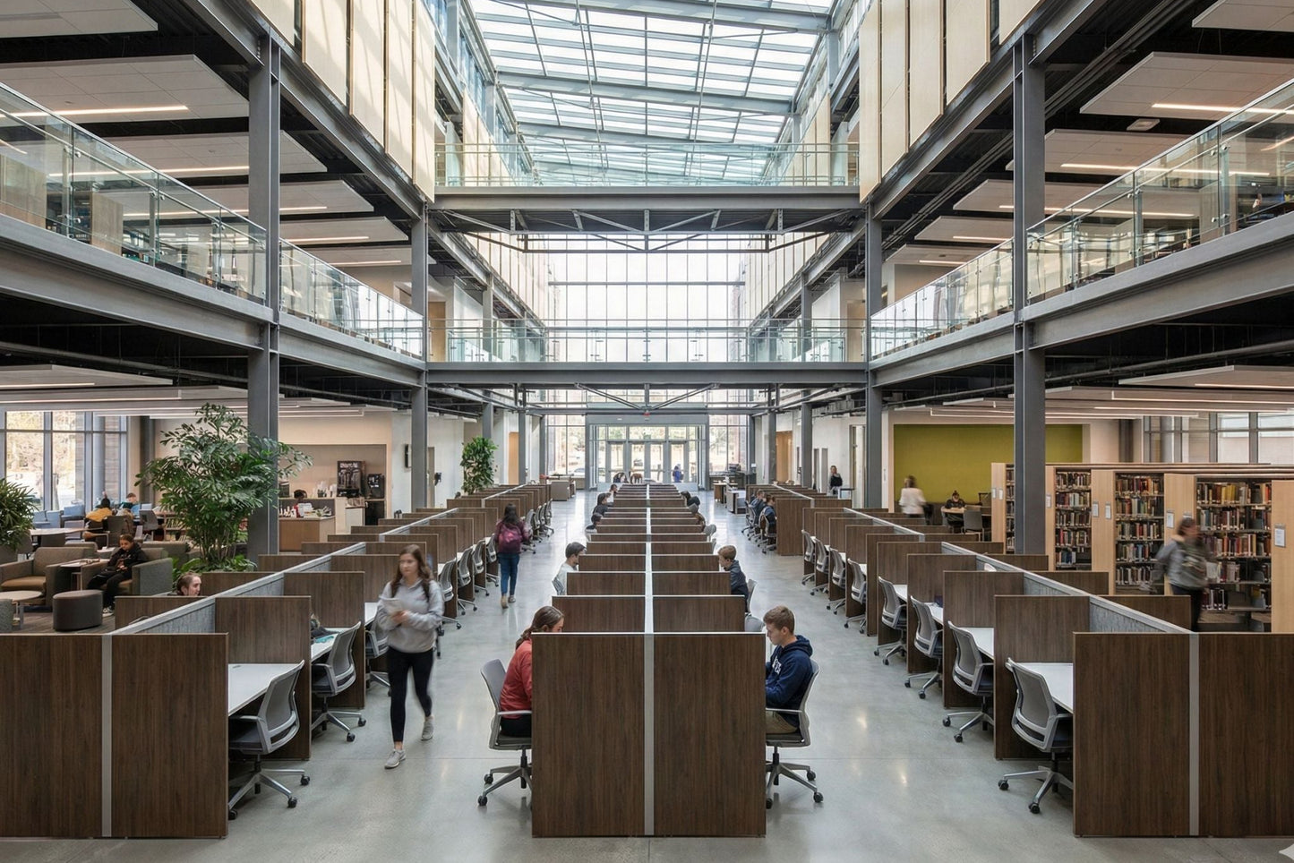 Modern library with high ceilings and large windows, people studying at desks.
