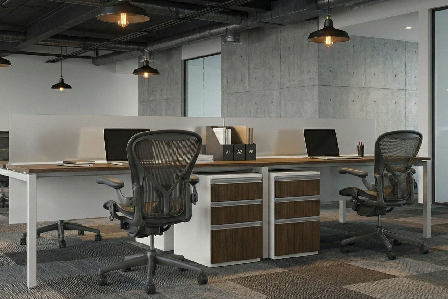 Modern office benching space with desks, chairs, and computer monitors.