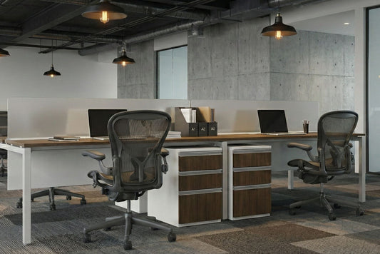 Modern office benching space with desks, chairs, and computer monitors.