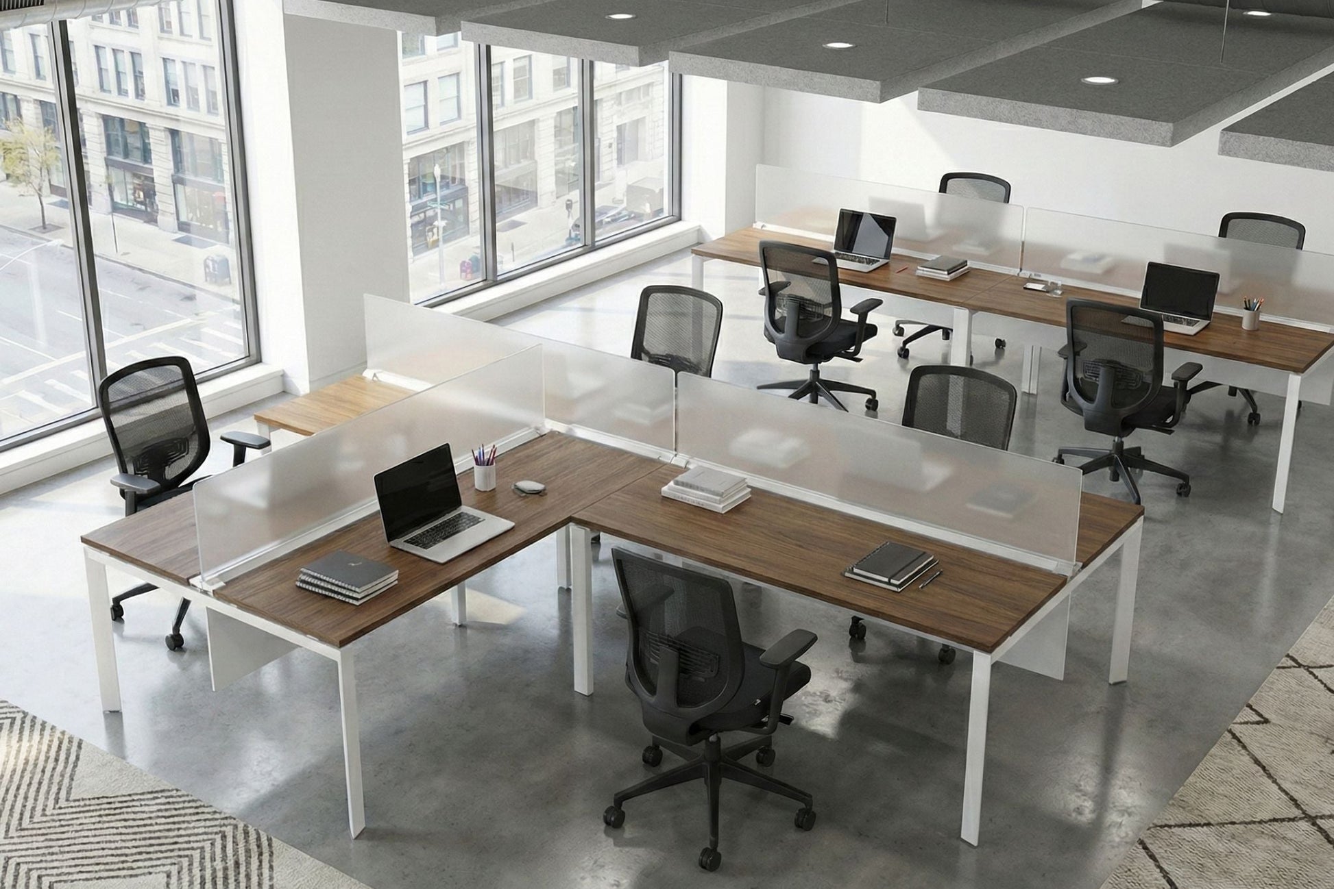 Modern office with L-shaped desks, chairs, and large windows.