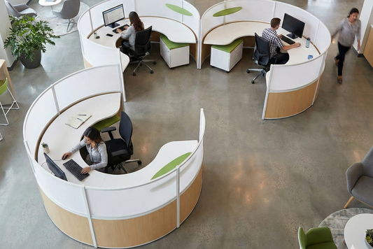 Modern office space with round workstations and employees using computers.