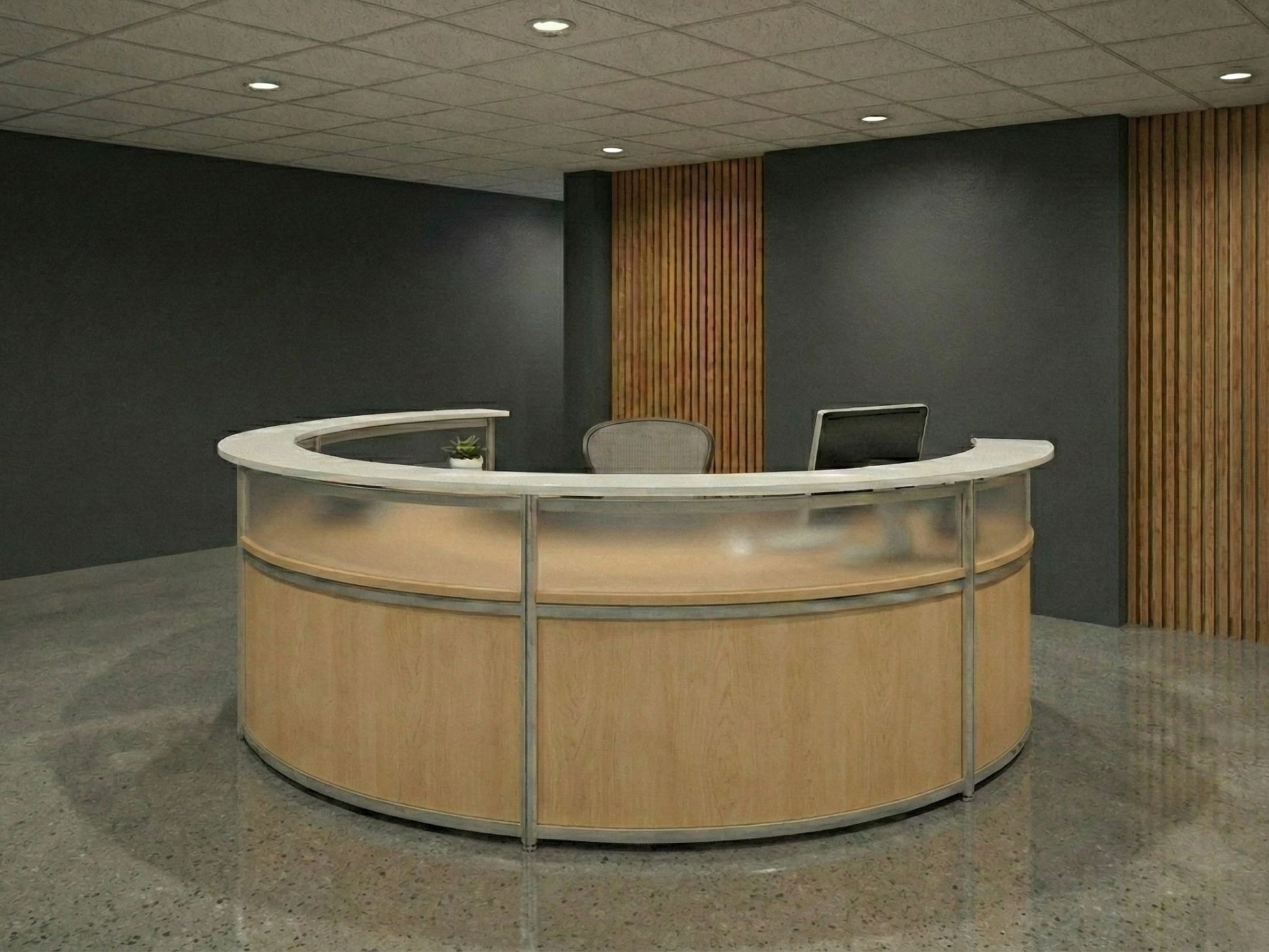 Curved reception desk with a laptop on a gray floor and dark walls.