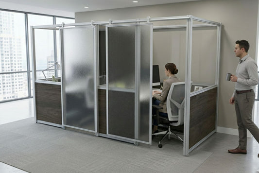 Person working at a desk in a modern office with glass partition walls.