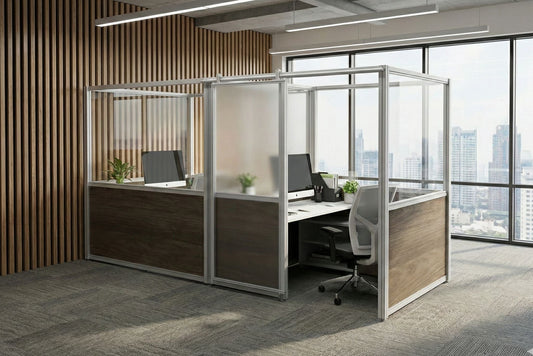 Modern office cubicle with desk, chair, and computer setup in a bright room with large windows.