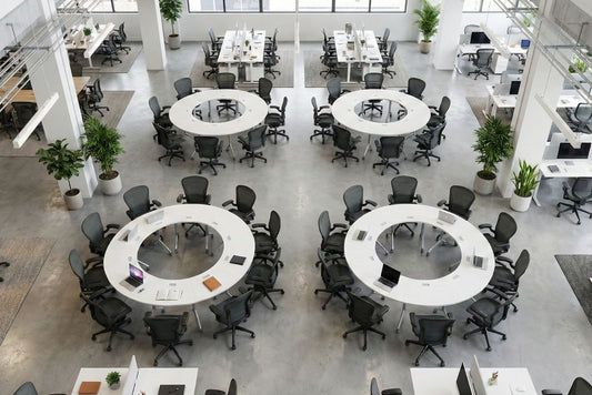 Modern office  training room space with round tables and chairs, large windows, and plants.