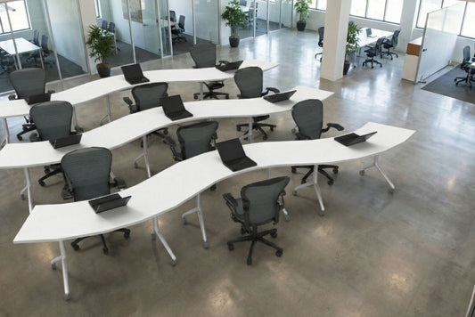 Modern office training room layout with curved white desks and black chairs in a large open space,